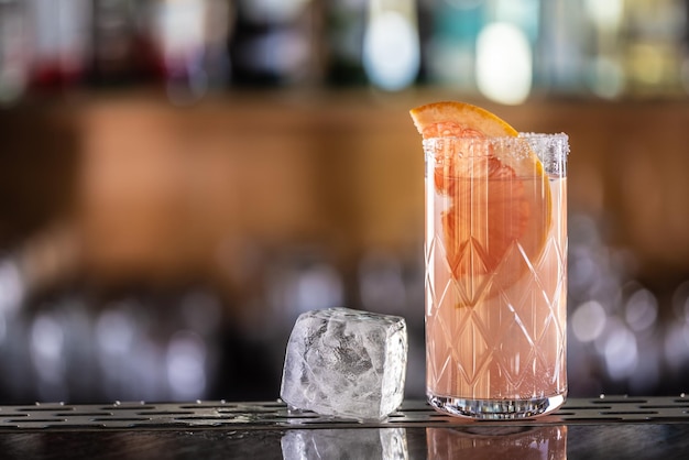 Paloma cocktail with tequila garnished with grapefruit on the bar counter an ice cube led the drink