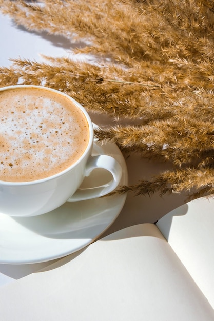 Фото Пампа трава и белая чашка с кофе пустая тетрадь делает план для дня питья