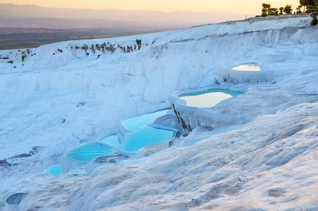 Pamukkale natural travertine terraces filled with blue water at sunset