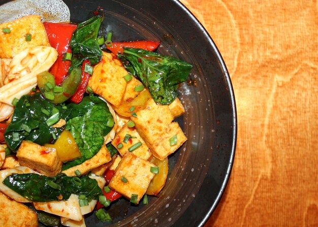 pan aziatisch gerecht met tofu, inktvis, garnalen, spinazie, groene ui, zoete paprika en pikante saus