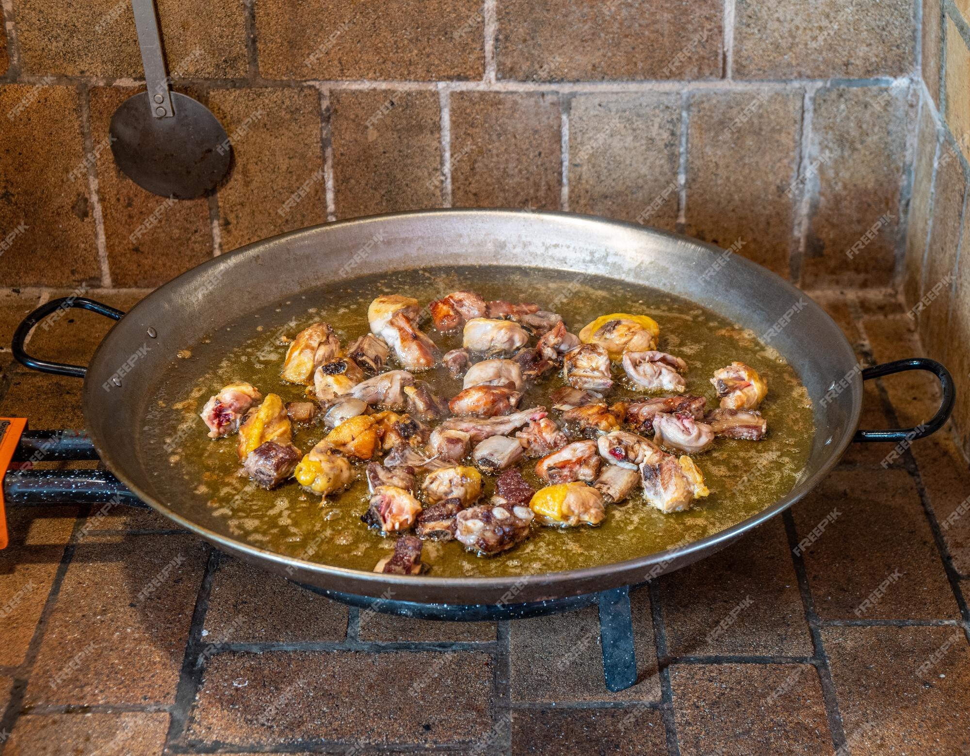 Premium Photo | A pan of chicken and chicken cooking on a stove.