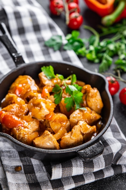 A pan of chicken with vegetables on a black and white checkered tablecloth.