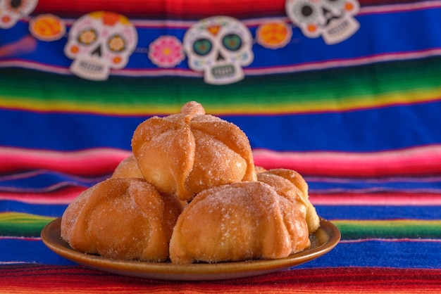 Pan de muerto with sugar skull figures on colorful serape day of the dead celebration