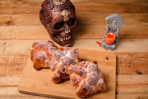 Pan de muertos와 나무 테이블에 그려진 해골. 망자의 날 축하의 전형적인 디저트