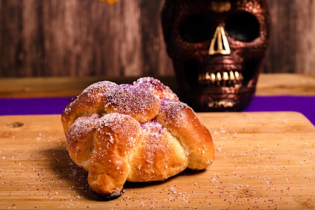 Pan de muertos와 나무 테이블에 그려진 해골. 망자의 날 축하의 전형적인 디저트