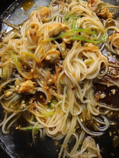 Foto una padella piena di tagliatelle e carne in cima a una stufa