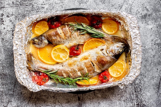 A pan of fish with vegetables and herbs on top