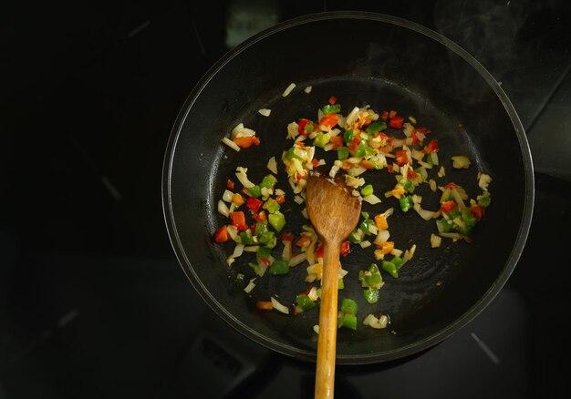 Foto una padella di cibo viene cucinata con un cucchiaio di legno