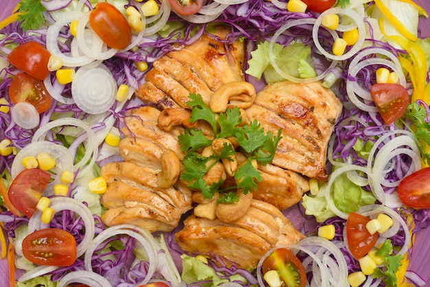 Жареная курица с зеленью и овощами крупным планом на фиолетовой тарелке