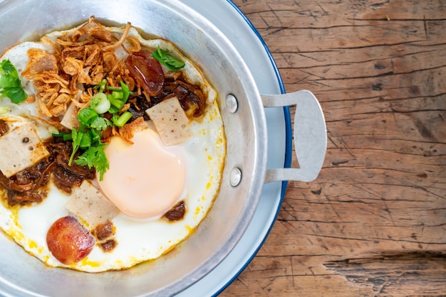 Pan Fried Egg topping with Thai sausage on wood surface