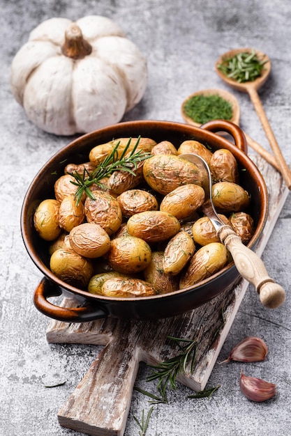 Pan gevuld met geroosterde aardappelen geschoten op rustieke houten tafel De ingrediënten zijn onder meer rauwe aardappelen rozemarijn dille zout peper en knoflook