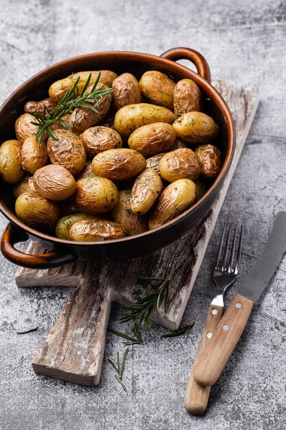 Pan gevuld met geroosterde aardappelen geschoten op rustieke houten tafel De ingrediënten zijn onder meer rauwe aardappelen rozemarijn dille zout peper en knoflook