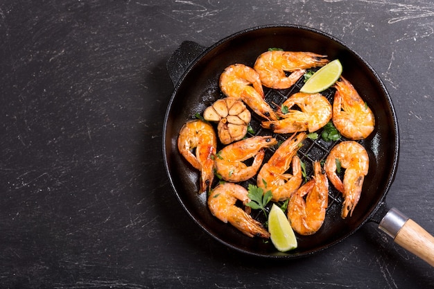 Pan of grilled shrimps on a dark table