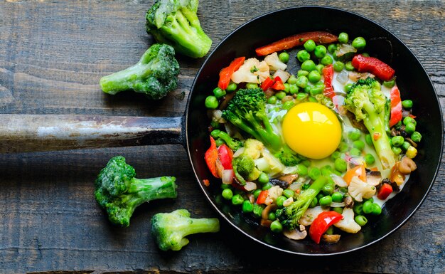 Pan met gebakken ei en een plantaardig mengsel: pinda's, broccoli, paprika en bevroren broccoli