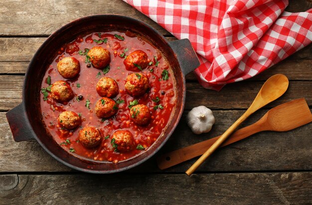 Pan met gehaktballen in tomatensaus op houten achtergrond