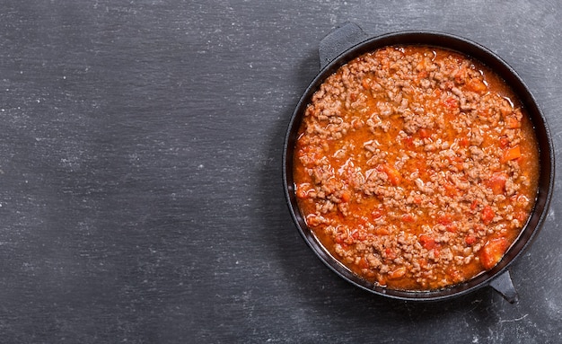 Pan met saus bolognese op donkere, bovenaanzicht met kopie ruimte