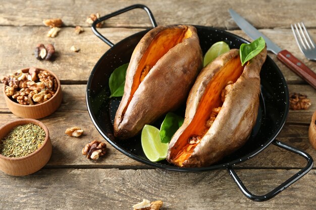 Pan with baked sweet potato on wooden table