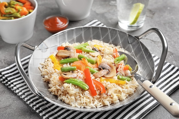 Pan with brown rice and vegetables on table