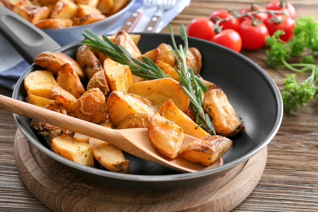 Padella con deliziose patate al rosmarino sulla tavola di legno