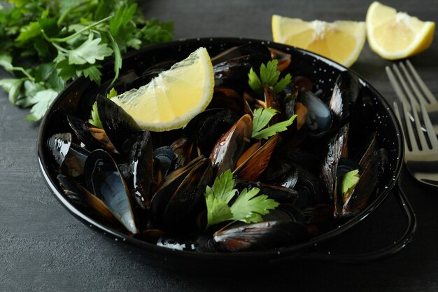 Pan with fresh mussels on dark wooden table