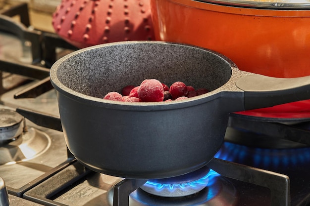 Pan with frozen berries on fire on gas stove