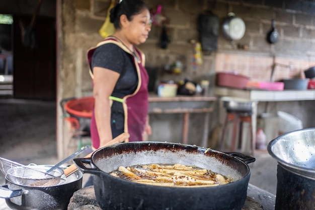 Pan with frying food next to a latin woman in a domestic poor kitchen Nicaragua