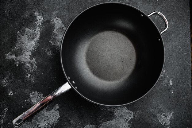 Pan with handle wok set with copy space for text or food with\
copy space for text or food, top view flat lay, on black dark stone\
table background