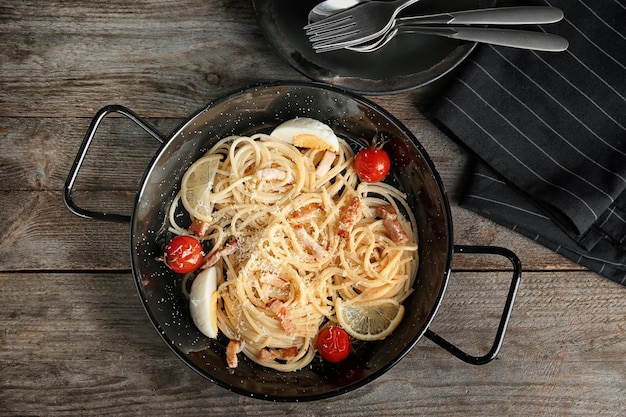 Pan with pasta carbonara and bacon on table