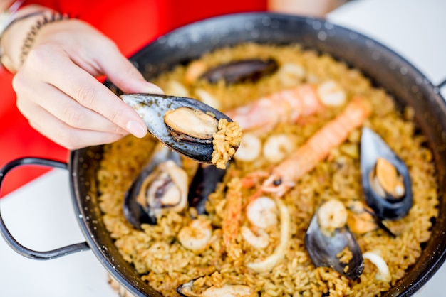 Padella con paella di mare, piatto di riso valenciano, sul tavolo bianco all'aperto