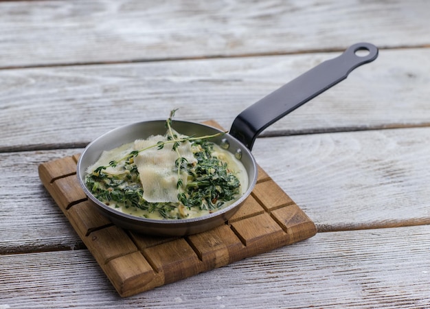 pan with spinach and cream sauce and parmesan cheese on a wooden board