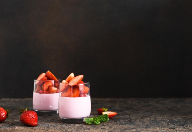 Pana cotta with strawberries and mint on a dark concrete background. Horizontal focus.