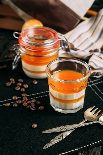 Dessert di panacotta con la pesca in un barattolo su un fondo scuro con gli elementi decorativi, vista laterale, verticale