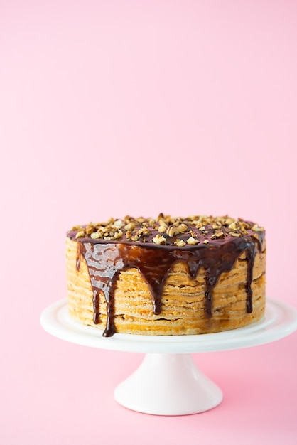 Pancake cake with caramel drops walnuts on a pink wall