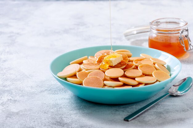 Pancake Cereal with Butter and Dripping Honey or Maple Syrup in Bowl