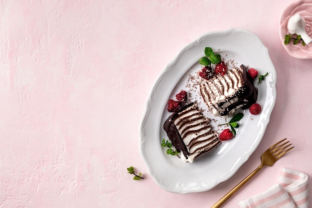 Pancake chocolate cake with fresh raspberries on a pink background