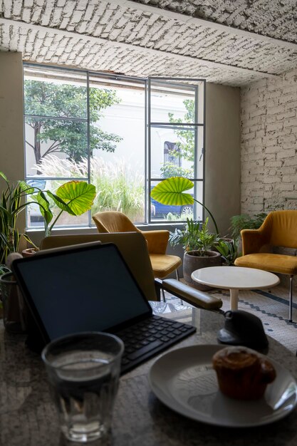 Pancake or cupcake on ceramic plate tablet in the back Enjoying sweet bread while working behind two armchairs