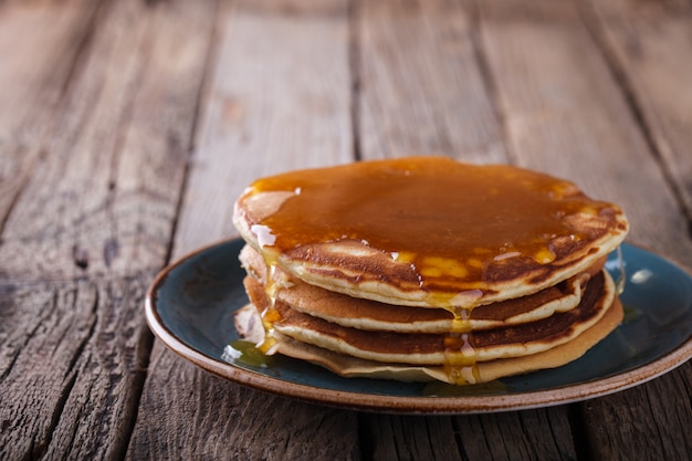 Pancake folded stack of with liquid honey on wooden background.