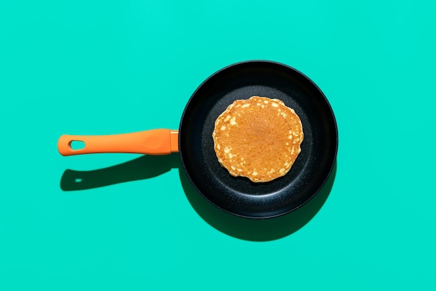 Pancake in a iron cast pan top view on a green colored background