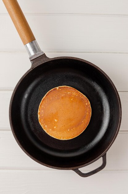 Pancake of oatmeal and bananas fried in a frying pan on a\
wooden background recipe step by step