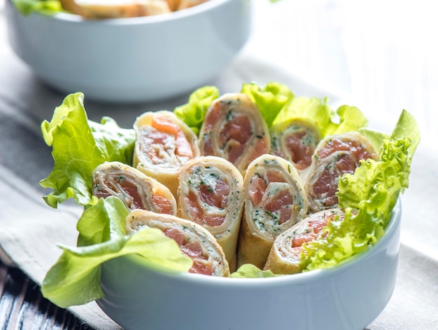 Pancake rolls with salmon and greens in a white bowl