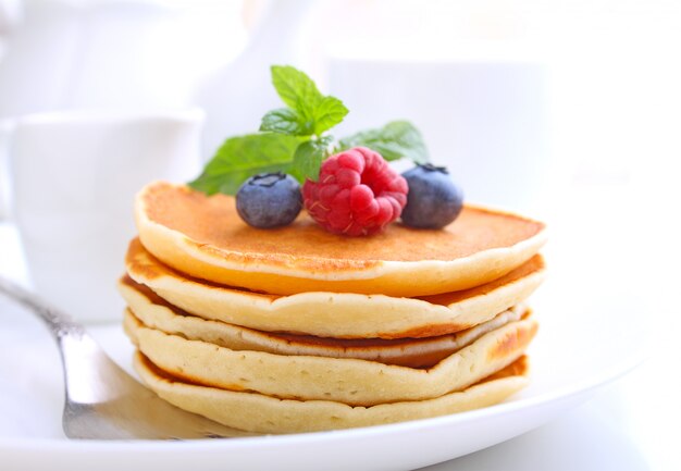 Pancake with berries blueberries in a plate on a white background