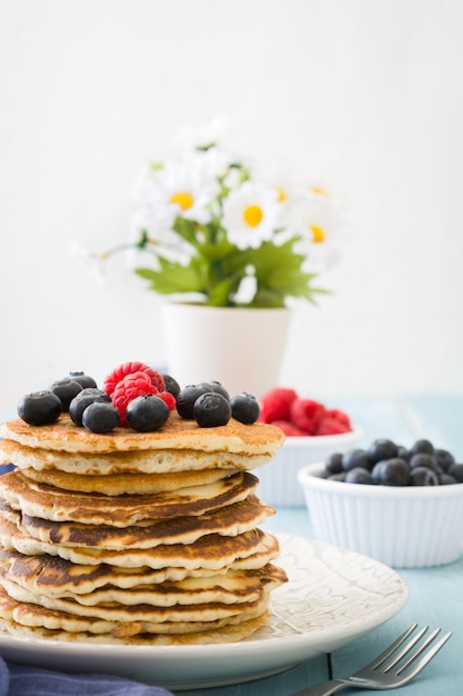 Pancake with blueberries and raspberries on blue wooden table