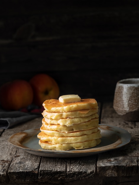 Pancake with butter. Dark moody old rustic wooden background.