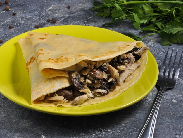 Pancake with chicken and mushrooms on a gray background