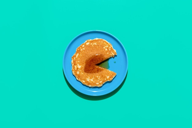 Pancake with mapple syrup on a blue table above view