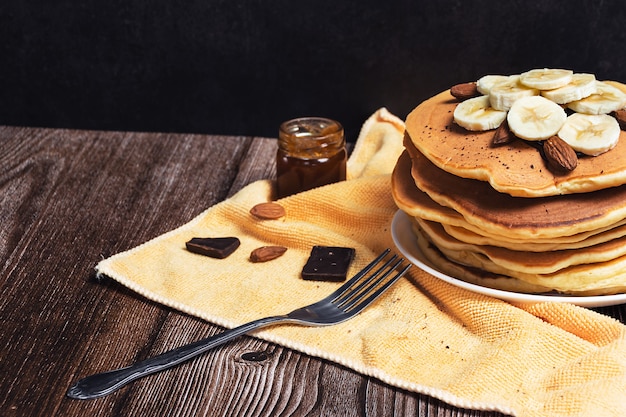 Frittella su una tavola di legno, al buio, con banane e cioccolato