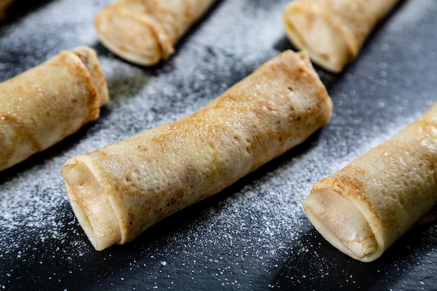 Pancakes on black background with surar powder