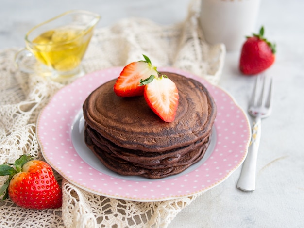 Pancakes from bird cherry flour with strawberries and honey. Healthy breakfast. Close up.