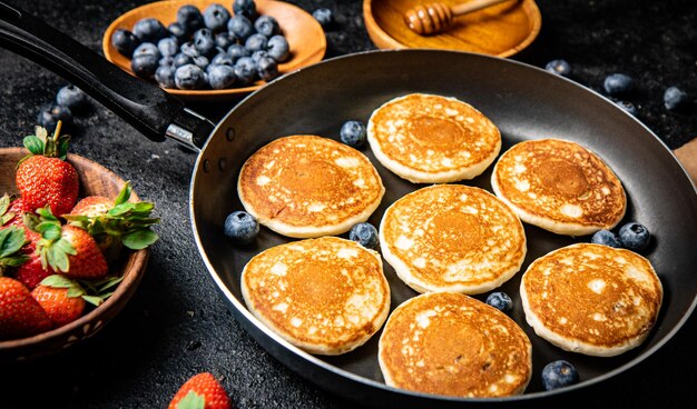 Photo pancakes in a frying pan with fresh berries and honey