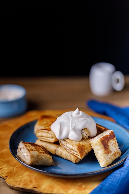 Pancakes met kaasvulling en zure room op een blauw bord